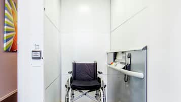 A wheelchair-accessible elevator with a handrail and a control panel.