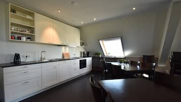 A modern kitchen with white cabinets, a dining area with a table and chairs, and a window providing natural light.