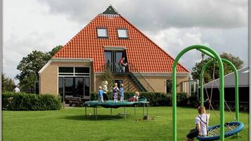 A house with a red-tiled roof, a front porch, and a swing set in the yard.