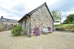 A stone building with a sloped roof, a gravel driveway, and a small garden area with a bench. - Holiday Home Saint-gilles Near Beach (Saint-Gilles-les-Bois)