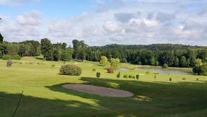 Een golfbaan met een vijver, bomen en een heldere lucht.