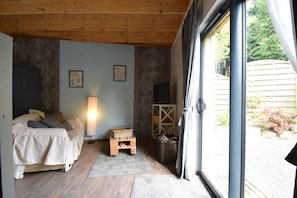 A bedroom with a bed, a lamp, a wooden cabinet, and a wicker basket. - Holiday Home Saint-gilles Near Beach (Saint-Gilles-les-Bois)