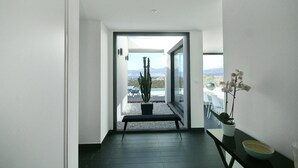 Un intérieur moderne avec un banc, des plantes en pot et une vue sur un espace extérieur.