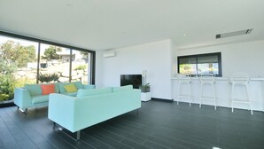 Un salon moderne avec un canapé, un téléviseur et un coin bar équipé de tabourets.