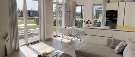 A modern living room with a glass coffee table, a sofa, and a dining area with a table and chairs.