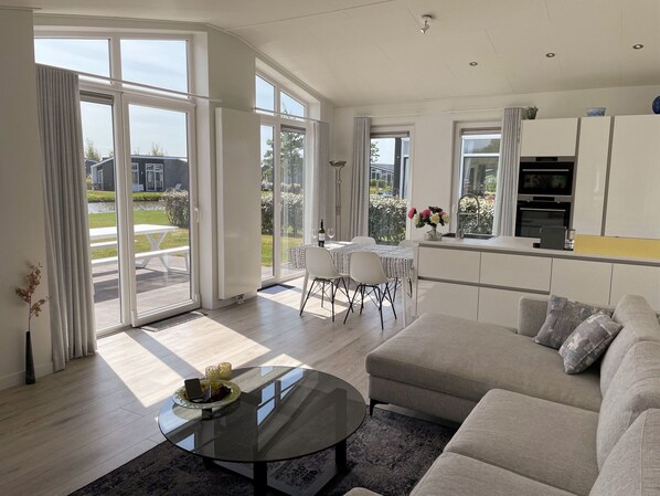 A modern living room with a glass coffee table, a sofa, and a dining area with a table and chairs.