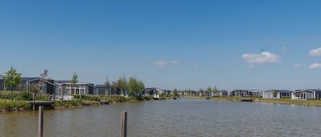 Un quartier résidentiel au bord du lac, avec des maisons modernes, une jetée en bois et un ciel bleu dégagé.