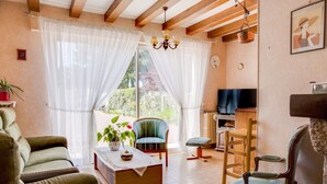 A living room with a sofa, chairs, a television, and a large window with curtains. - Beachside Family Retreat (Penestin)