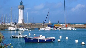 A harbor with boats, a lighthouse, and a stone wall. - Beachside Family Retreat (Penestin)