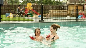 A swimming pool with a child and an adult. - Tidy Chalet with Microwave near Wadden Sea (Tzummarum)