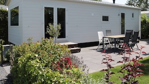 A small, single-story mobile home with a patio area. - Tidy Chalet with Microwave near Wadden Sea (Tzummarum)