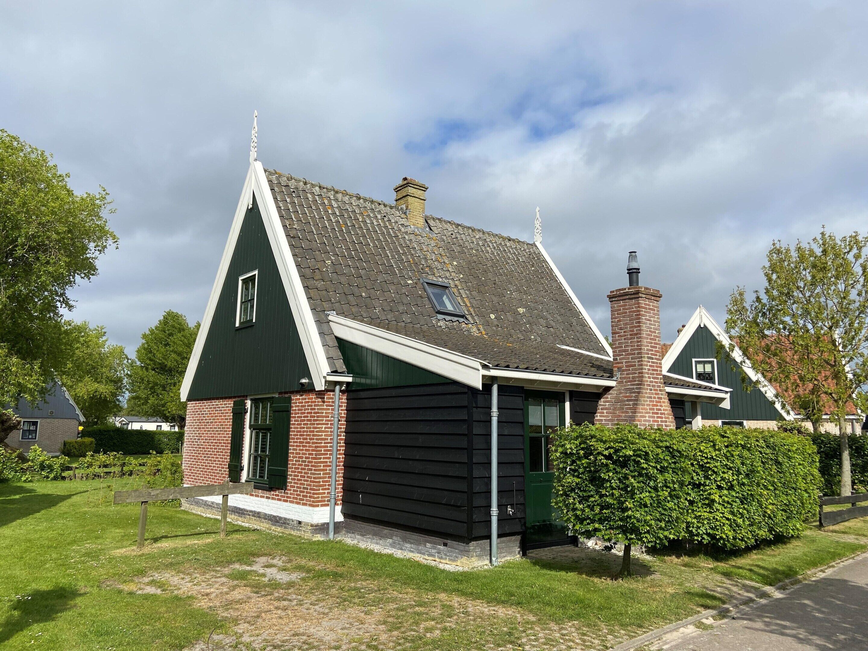 A traditional house with a steeply pitched roof, a brick chimney, and a small window.