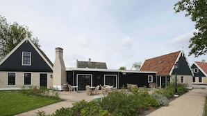 A traditional building with a black facade, a chimney, and a covered patio area with outdoor seating. - Modern Dutch Villa With Terrace (Hippolytushoef)