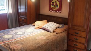 Ein Schlafzimmer mit einem Bett, Kissen, einem Wandposter und Holzmöbeln.