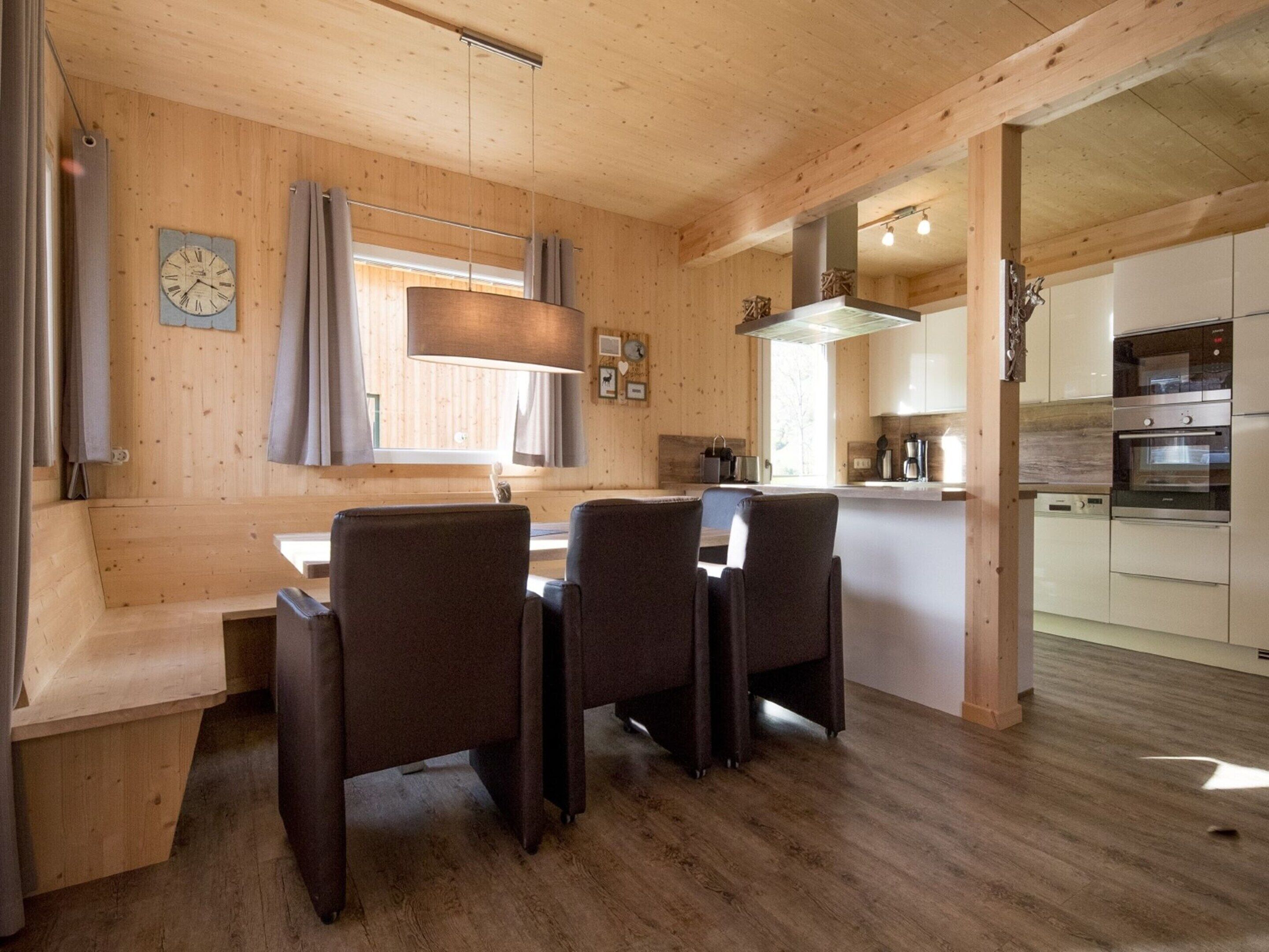 Un intérieur en bois comprenant un coin repas, une cuisine et une horloge au mur.