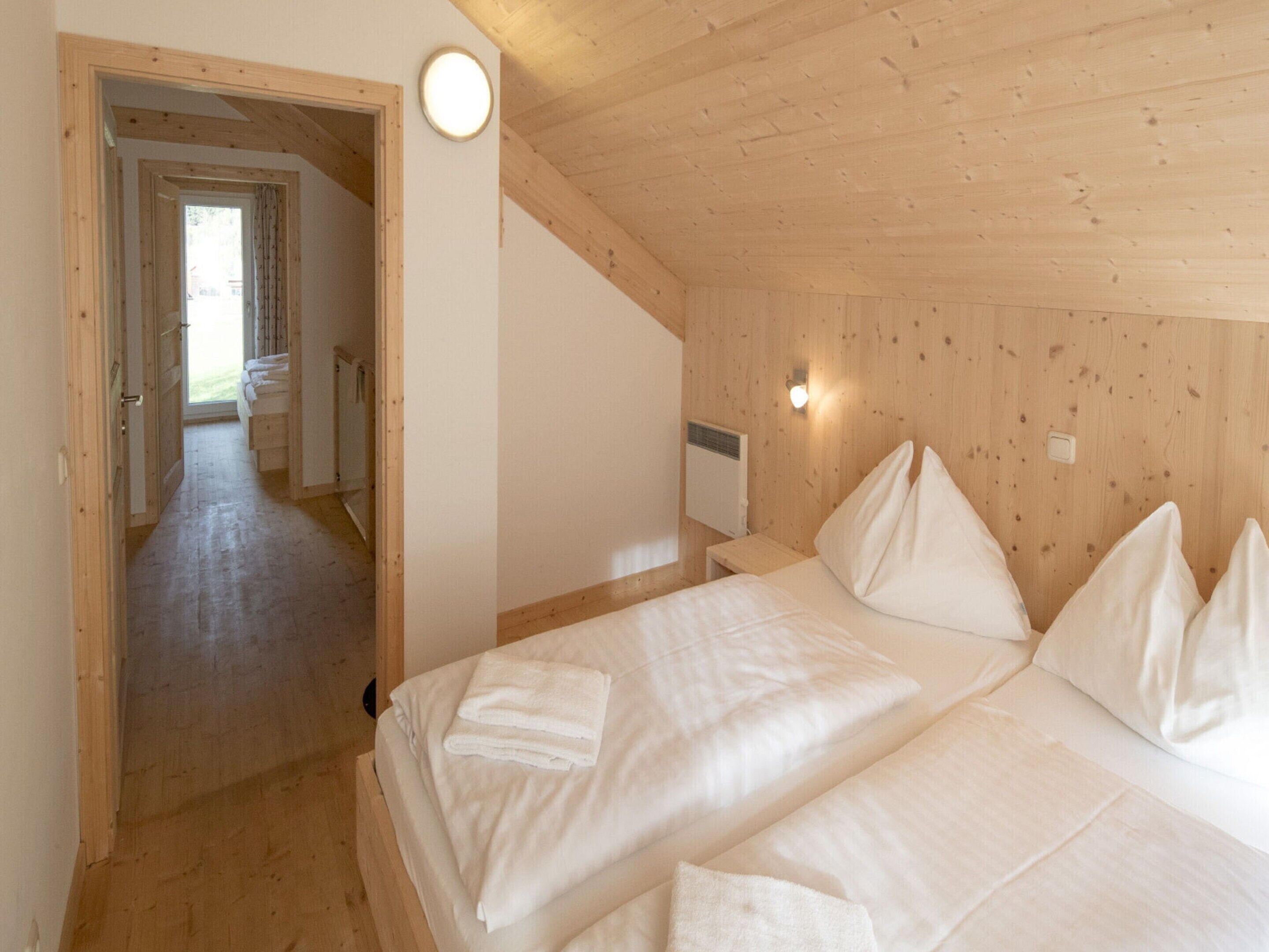 A wooden cabin bedroom with a bed, pillows, and a nightstand.
