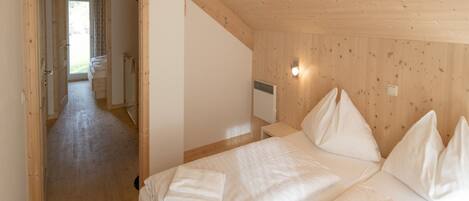 A wooden cabin bedroom with a bed, pillows, and a nightstand.