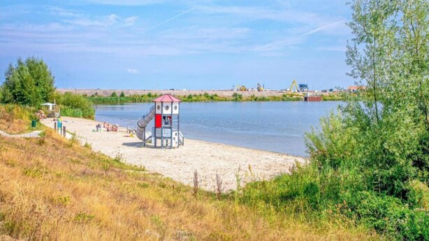 A riverside beach with a lifeguard tower, sandy shore, and greenery. - Cozy Villa in Wieringer Style near Wadden Sea (Hippolytushoef)