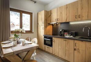 A modern kitchen with wooden cabinets, a built-in oven, and a window with a view of a snowy landscape. - Apartment in Beaufort Near Ski Slopes (Beaufort)