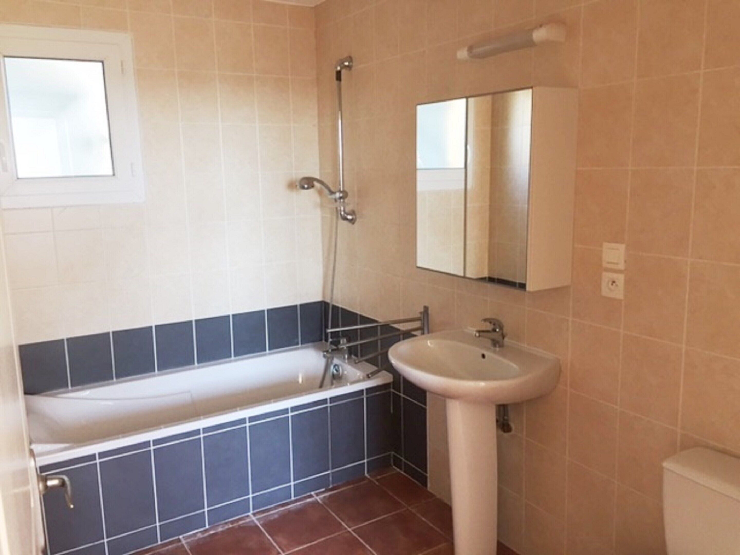 A bathroom with a bathtub, a sink, and a mirror.