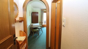 Un couloir avec un banc en bois, une table avec des chaises et une porte donnant sur une autre pièce.