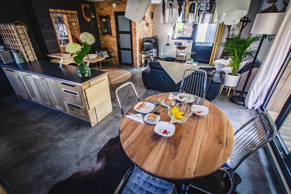 A modern kitchen with a dining area, wooden furniture, and a large window. - Saint-quirin Garden Stay (Saint-Quirin)