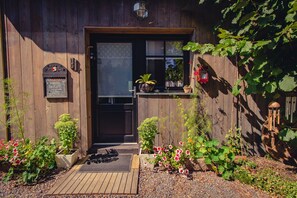Un bâtiment en bois avec une porte noire, une petite fenêtre et une enseigne.