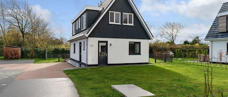 A modern two-story house with a black and white exterior, a well-maintained lawn, and a paved driveway.