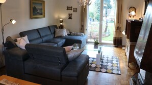 Una sala moderna con un sofá seccional, una mesa de centro de vidrio y un ventanal con cortinas.