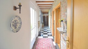 Un pasillo con piso a cuadros, un tapete estampado y una lámpara de pared.