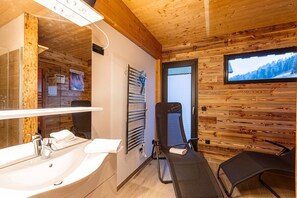 A wooden cabin interior with a sink, towel rack, and a TV displaying a snowy landscape. - Chalet in Hohentauern With Sauna (Hohentauern)