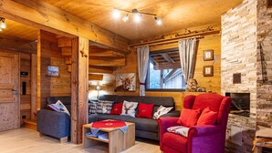 A cozy log cabin interior with a sofa, armchair, and fireplace. - Chalet in Hohentauern With Sauna (Hohentauern)