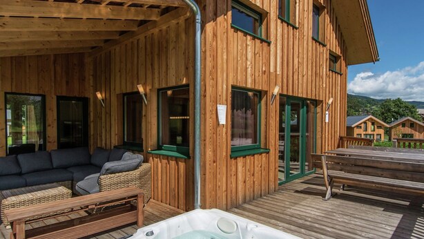 A wooden cabin with a hot tub, outdoor seating, and a view of the surrounding landscape. - Spectacular Chalet near Ski Area in Sankt Georgen ob Murau (Sankt Georgen am Kreischberg)