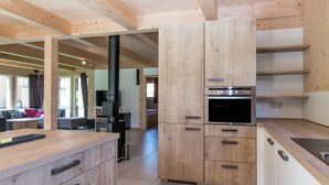 A modern kitchen with wooden cabinets, a built-in oven, and a large window. - Spectacular Chalet near Ski Area in Sankt Georgen ob Murau (Sankt Georgen am Kreischberg)