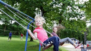 Ein Spielplatz mit Schaukeln und einer Rasenfläche.