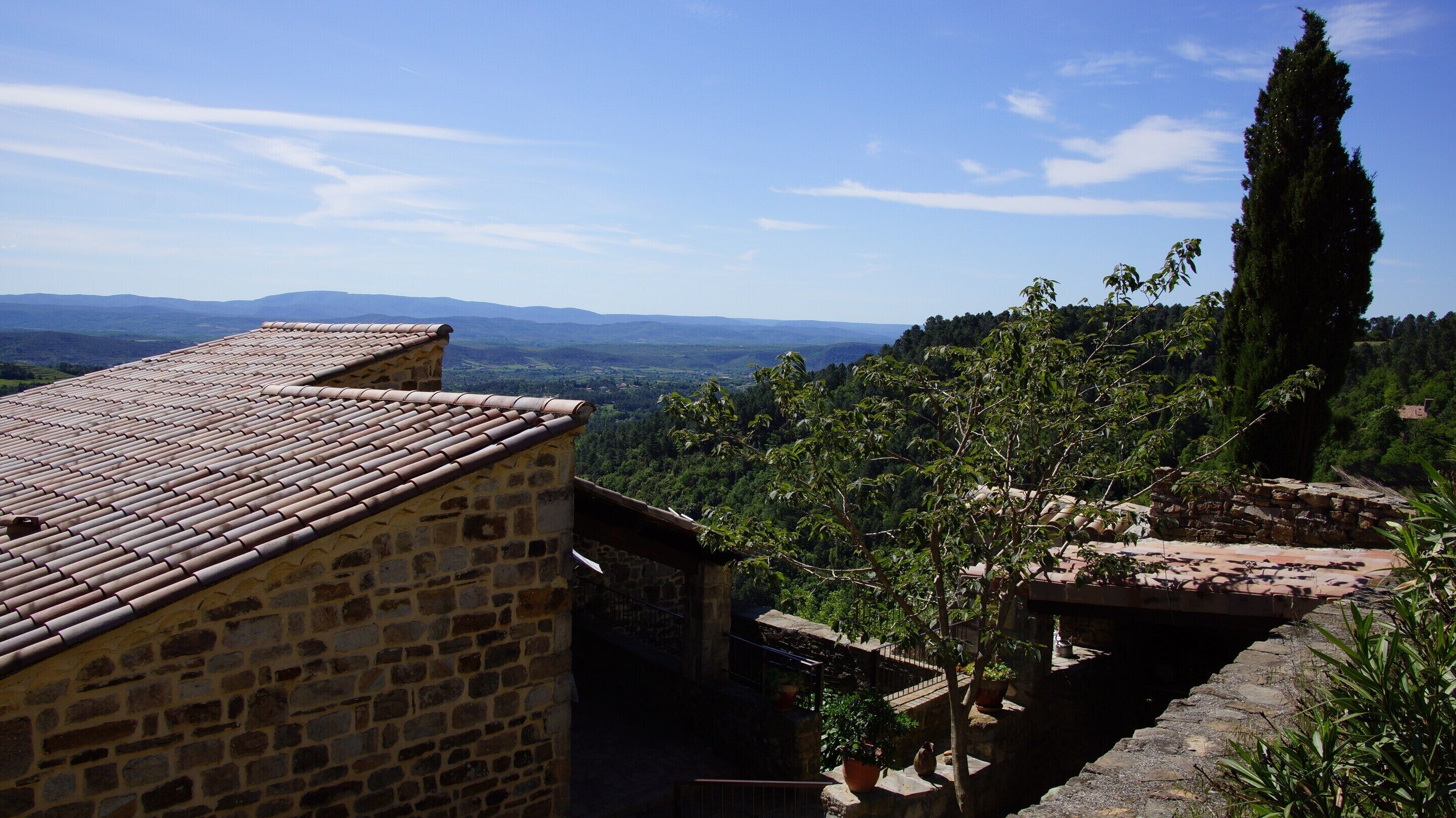 Un edificio de piedra con techo de tejas, con vistas a un paisaje montañoso.