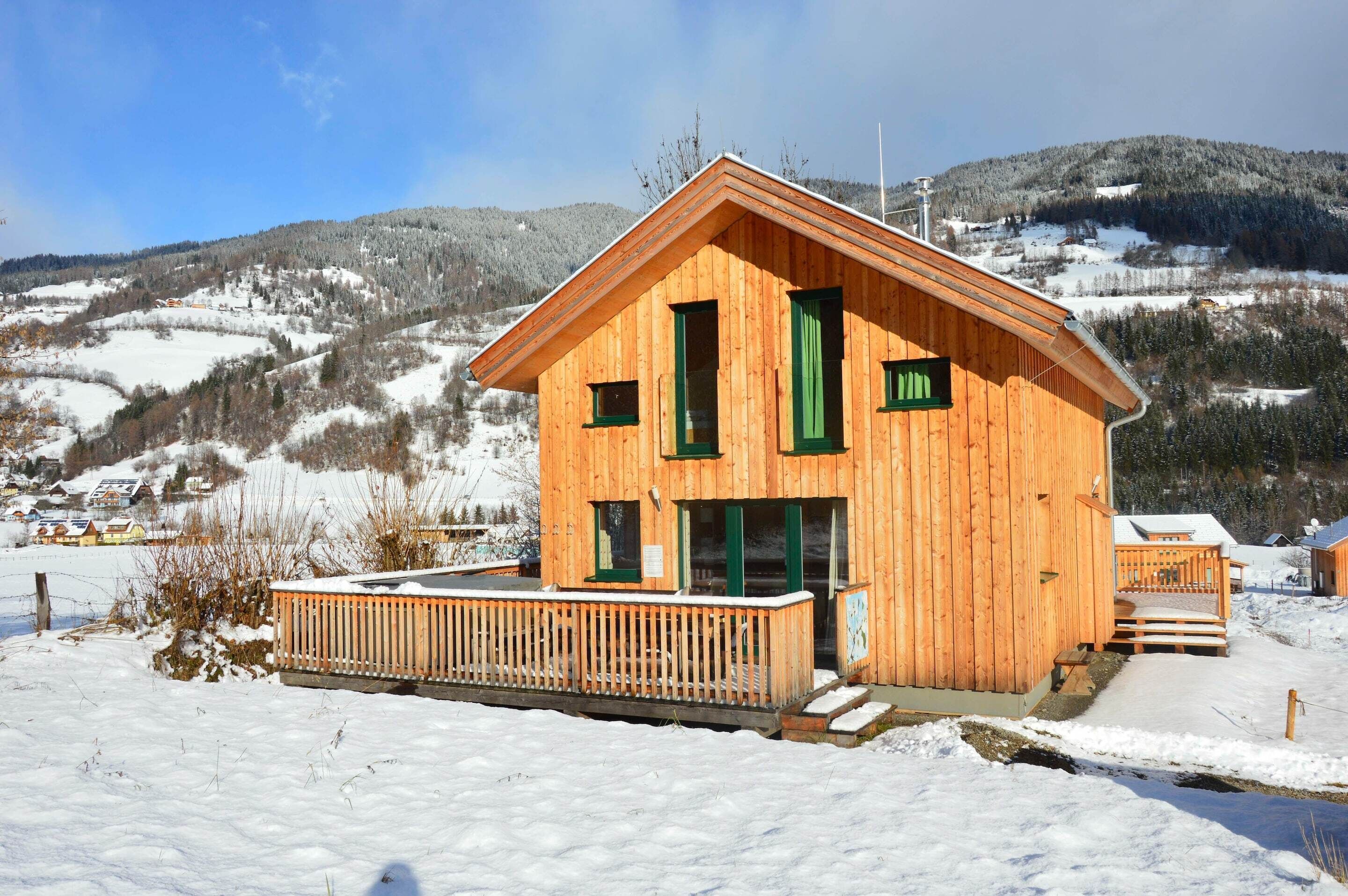 Eine Holzdiele mit Balkon, umgeben von schneebedeckten Hügeln.