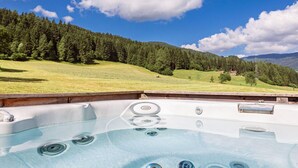 Un jacuzzi con vistas despejadas a un paisaje montañoso y una zona boscosa al fondo.