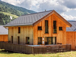 A wooden cabin with a sloped roof, large windows, and a wooden deck. - Modern Chalet With Infrared Sauna (Sankt Georgen am Kreischberg)