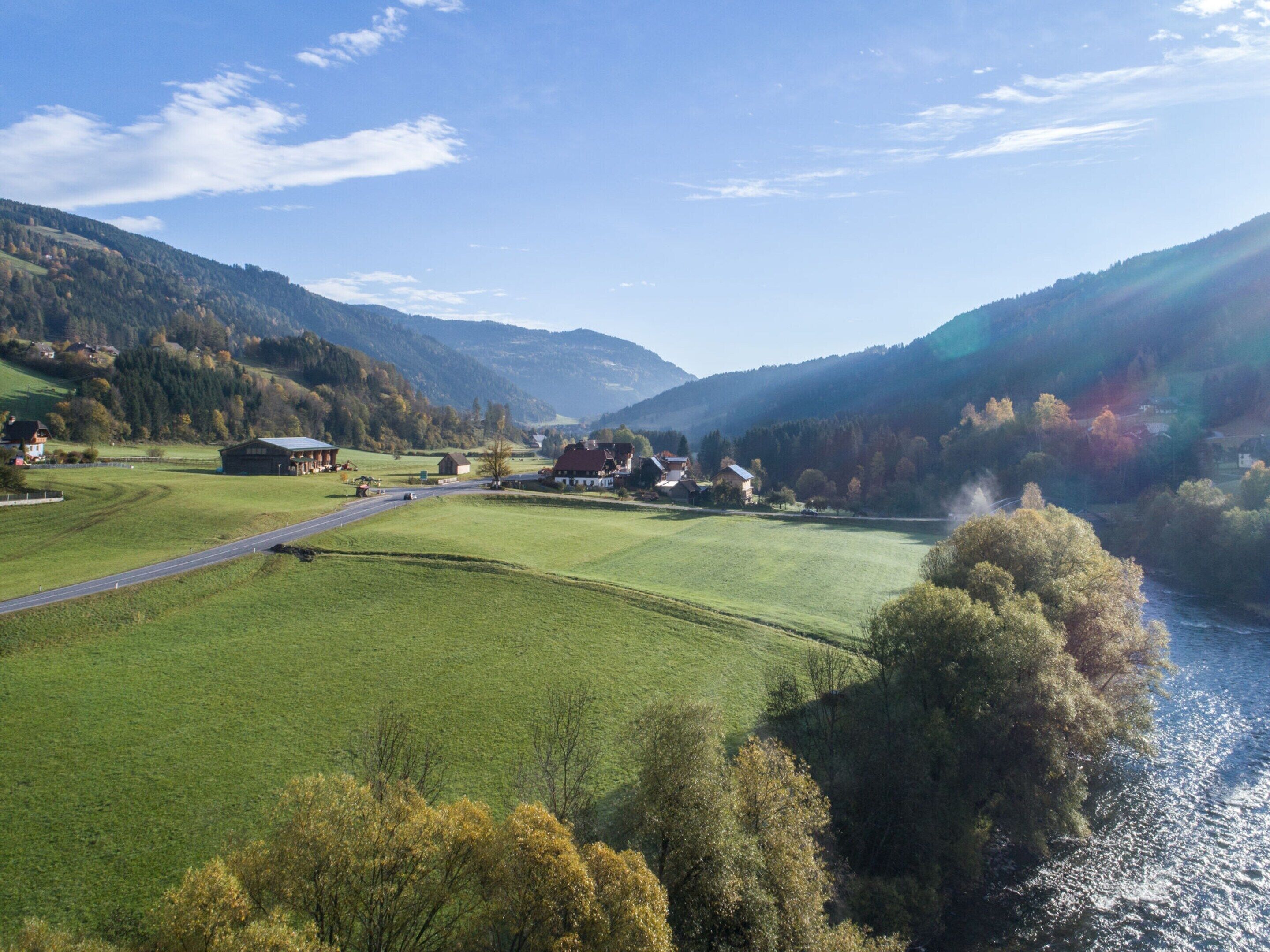 Un paysage rural avec une rivière, des maisons et des champs verdoyants.