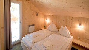 A room with two beds, a window with curtains, a wall-mounted heater, and a small table with a plant. - Beautiful Chalet With hot tub (Sankt Georgen am Kreischberg)
