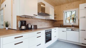 A modern kitchen with white cabinetry, a built-in oven, and a coffee maker. - Beautiful Chalet With hot tub (Sankt Georgen am Kreischberg)