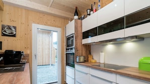 A modern kitchen with wooden walls, white cabinets, and a stainless steel range hood. - Attractive Chalet With hot tub (Sankt Georgen am Kreischberg)
