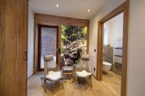 Relax in a serene space with a shower area featuring a scenic mural and two comfortable chairs.
