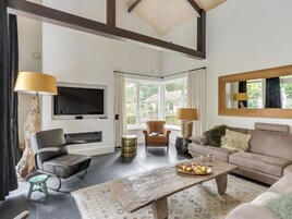Una sala de estar con televisión, sofá, sillón, mesa de centro y chimenea.