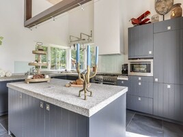 Una cocina moderna con una isla central, electrodomésticos integrados y un amplio ventanal que proporciona luz natural.