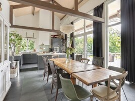 Una cocina amplia con una isla grande, electrodomésticos modernos y un comedor con mesa y sillas de madera.