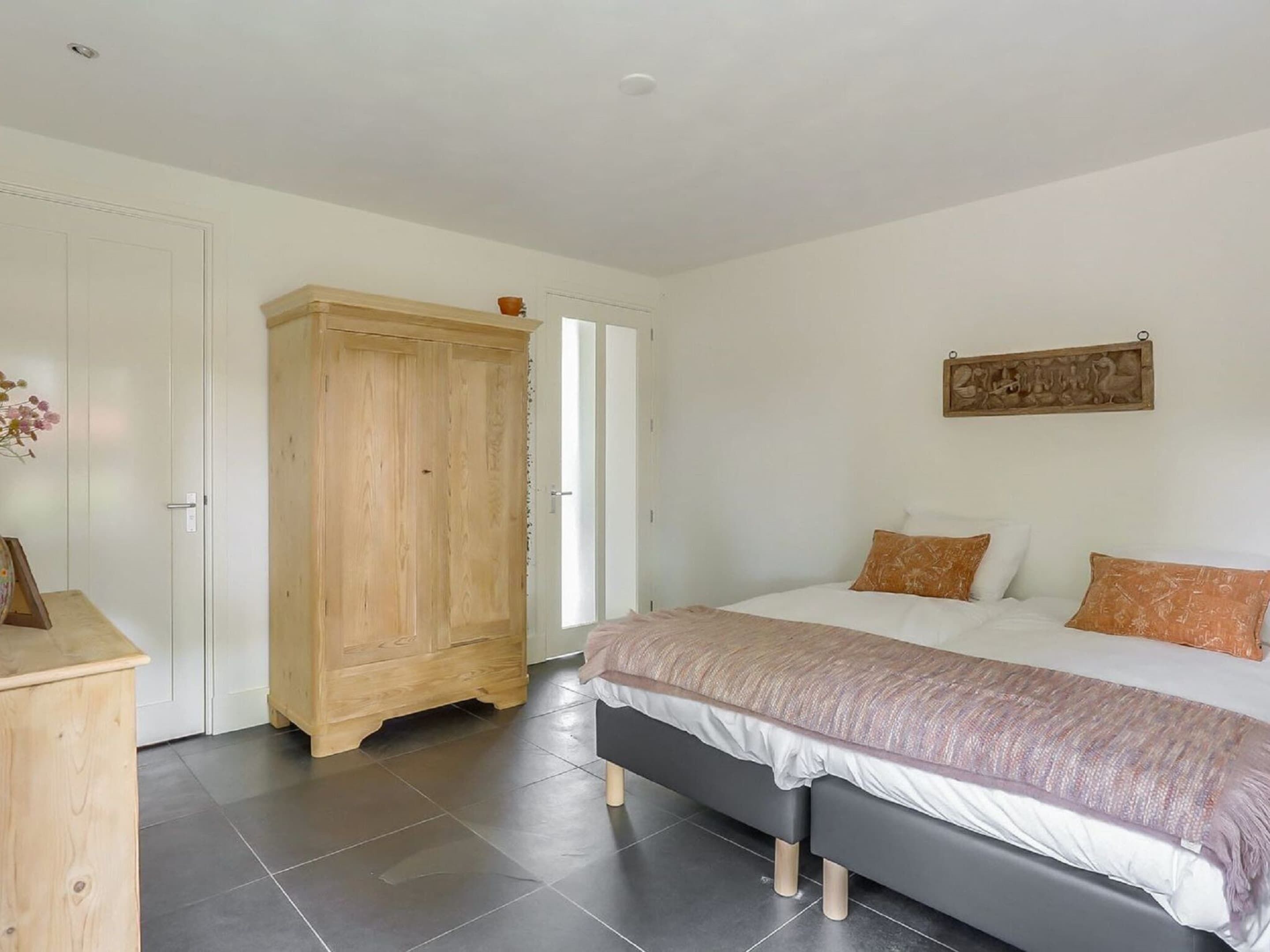 A bedroom with a bed, a wardrobe, and a painting on the wall.