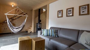 A cozy living room with a sofa, a hammock, and a fireplace. - Lovely Chalet With Infrared Sauna (Sankt Georgen am Kreischberg)