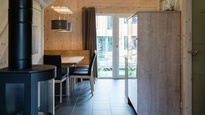 A modern kitchen with a wooden interior, a black stove, and a dining area with a table and chairs. - Lovely Chalet With Infrared Sauna (Sankt Georgen am Kreischberg)